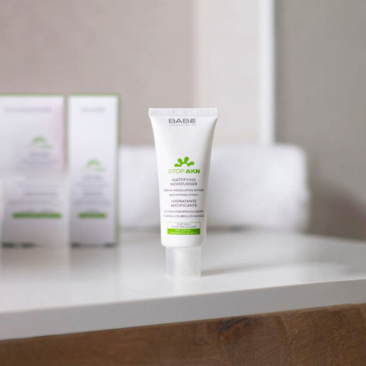 Image: A clean, clear bottle of Babé Purifying Cleansing Gel, surrounded by fresh green leaves, symbolizing purity and natural ingredients.